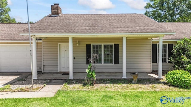 304 Ohara Dr, Albertville, AL 35950 - view of front of home featuring roof with shingles, covered porch, a garage, a chimney, and a front yard