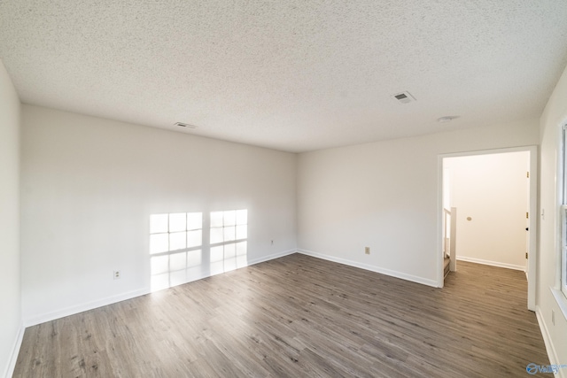 unfurnished room featuring dark hardwood / wood-style flooring and a textured ceiling