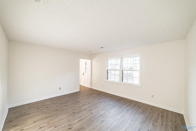 unfurnished room with wood-type flooring and a textured ceiling