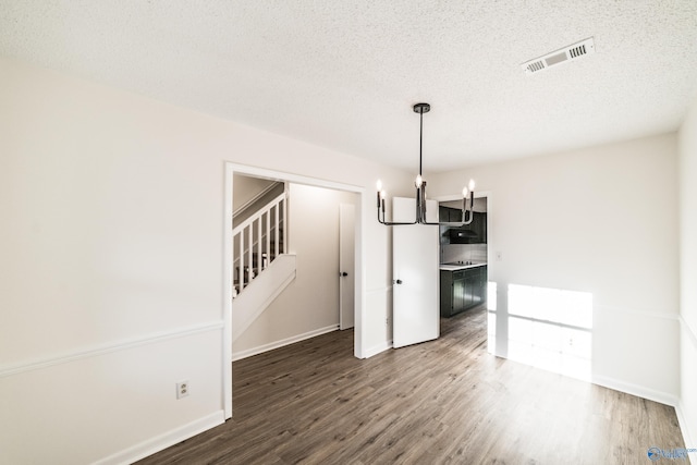 unfurnished dining area with a textured ceiling and dark wood-type flooring