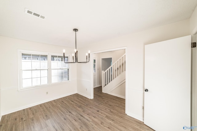 unfurnished dining area featuring a chandelier and hardwood / wood-style flooring