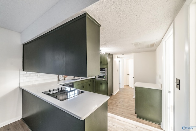 kitchen with stainless steel oven, green cabinets, light hardwood / wood-style flooring, kitchen peninsula, and black electric cooktop