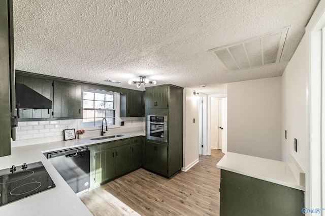 kitchen with sink, light hardwood / wood-style flooring, decorative backsplash, a textured ceiling, and stainless steel appliances