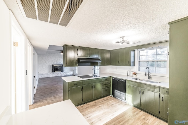 kitchen with a wood stove, sink, light hardwood / wood-style floors, black appliances, and green cabinetry