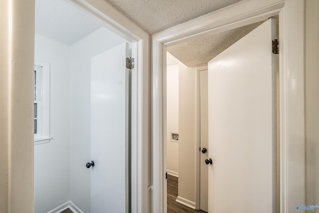 hall featuring a textured ceiling and dark wood-type flooring