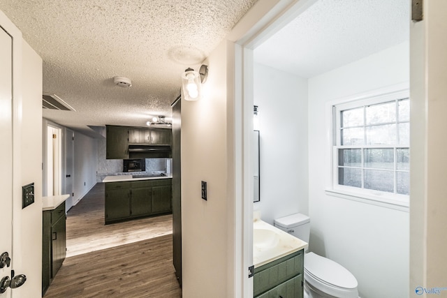 bathroom with hardwood / wood-style floors, vanity, a textured ceiling, and toilet