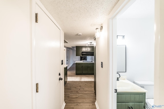 hallway featuring a textured ceiling, sink, and dark wood-type flooring