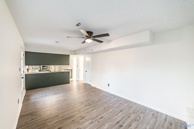 unfurnished living room featuring wood-type flooring, a textured ceiling, and ceiling fan