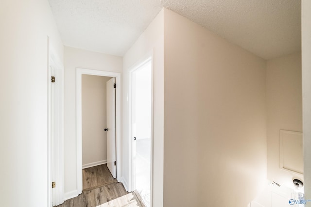 hallway with light hardwood / wood-style floors and a textured ceiling