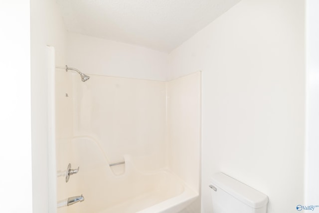 bathroom with bathtub / shower combination, a textured ceiling, and toilet