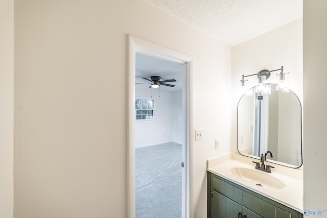 bathroom featuring ceiling fan, vanity, and a textured ceiling