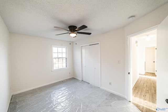 unfurnished bedroom featuring a textured ceiling, a closet, ceiling fan, and light hardwood / wood-style floors