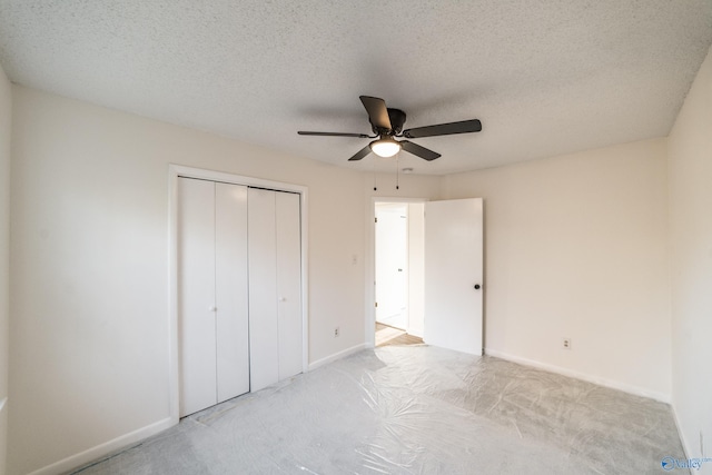 unfurnished bedroom featuring ceiling fan, a textured ceiling, light carpet, and a closet