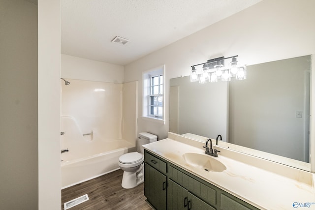 full bathroom featuring bathing tub / shower combination, a textured ceiling, toilet, vanity, and hardwood / wood-style flooring