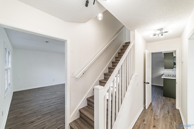 stairs featuring wood-type flooring and a textured ceiling