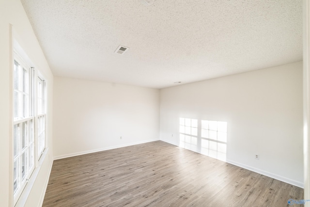 empty room with hardwood / wood-style floors and a textured ceiling