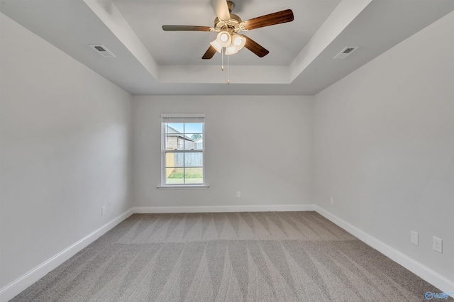 carpeted empty room with ceiling fan and a tray ceiling