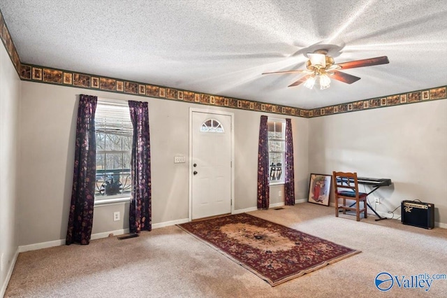 carpeted entryway featuring ceiling fan and a textured ceiling