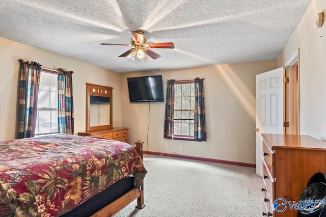 bedroom with multiple windows, ceiling fan, carpet flooring, and a textured ceiling