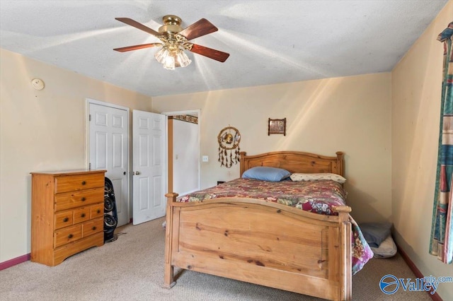 carpeted bedroom featuring ceiling fan and a textured ceiling