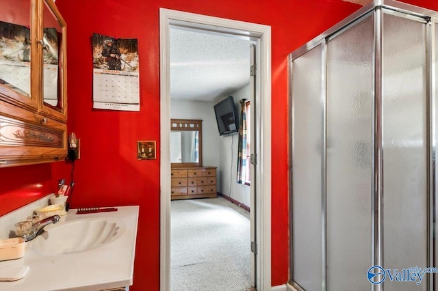 bathroom with a shower with shower door, sink, and a textured ceiling