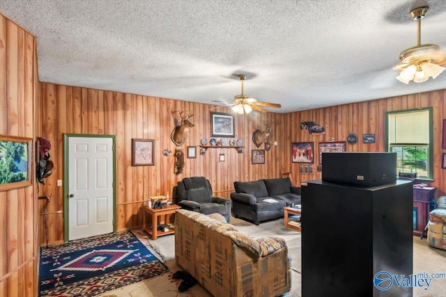 living room with a textured ceiling, ceiling fan, and wood walls