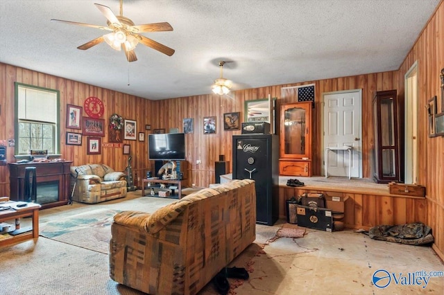 living room featuring ceiling fan, wooden walls, and a textured ceiling