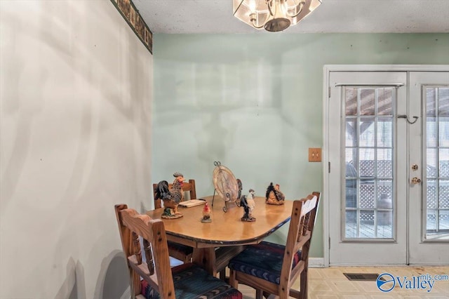 dining room featuring a notable chandelier, french doors, and a textured ceiling