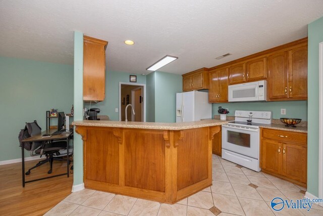 27586 Phillip Wagnon Dr, Athens, AL 35613 - kitchen with white appliances, light countertops, a breakfast bar area, a sink, and a peninsula