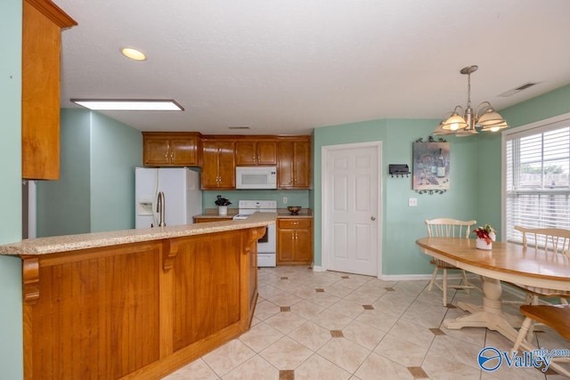 27586 Phillip Wagnon Dr, Athens, AL 35613 - kitchen featuring white appliances, light countertops, brown cabinets, a chandelier, and hanging light fixtures