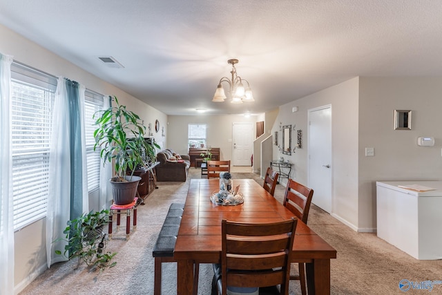 carpeted dining room featuring a textured ceiling, washer / clothes dryer, and a notable chandelier