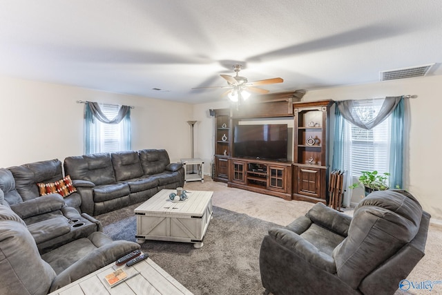 living room featuring carpet, ceiling fan, and a textured ceiling