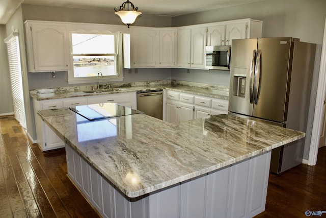 kitchen with decorative light fixtures, a kitchen island, sink, appliances with stainless steel finishes, and white cabinets