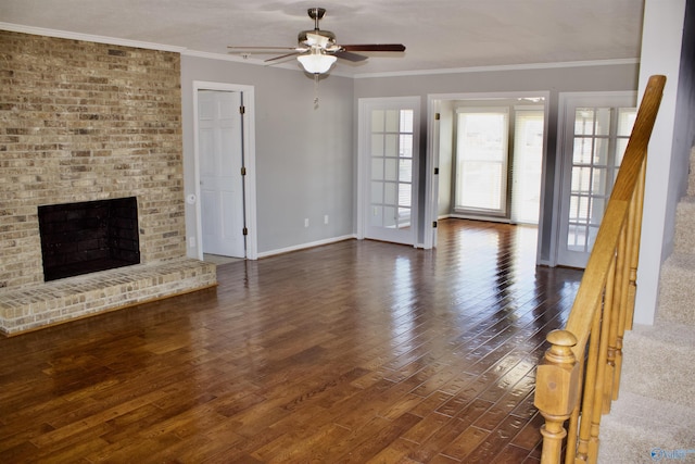 unfurnished living room featuring dark wood-type flooring, ceiling fan, a brick fireplace, and crown molding