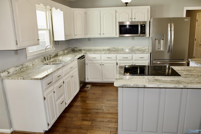 kitchen featuring appliances with stainless steel finishes, dark wood-type flooring, white cabinetry, sink, and light stone counters