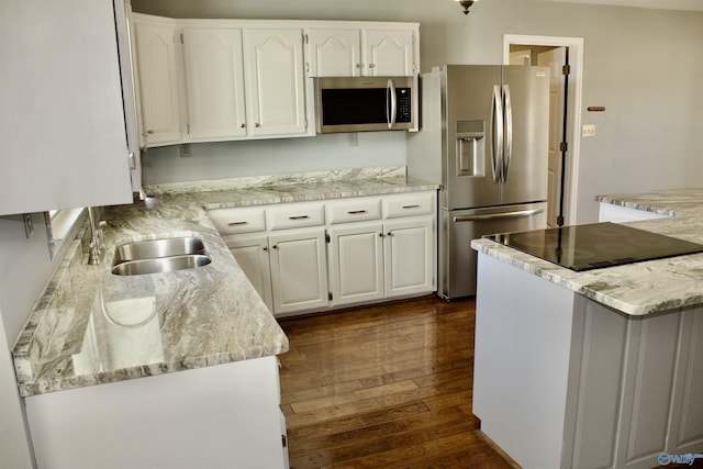 kitchen with sink, white cabinetry, appliances with stainless steel finishes, dark hardwood / wood-style flooring, and light stone counters