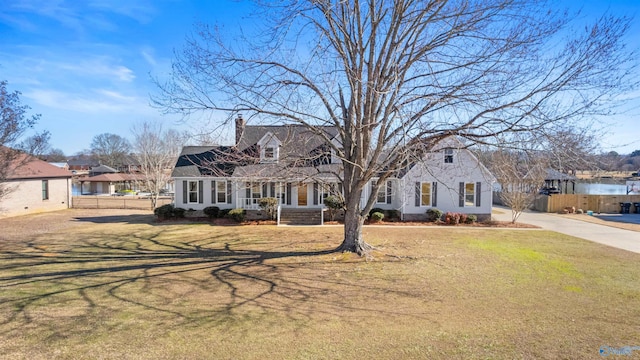 cape cod home featuring covered porch and a front lawn