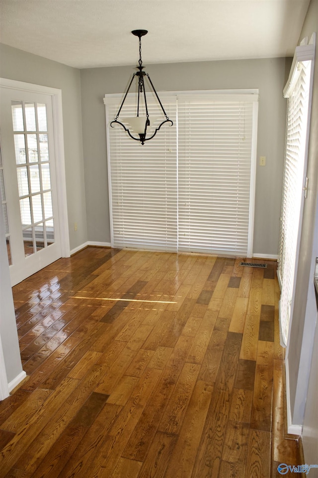 unfurnished dining area featuring dark wood-type flooring and an inviting chandelier