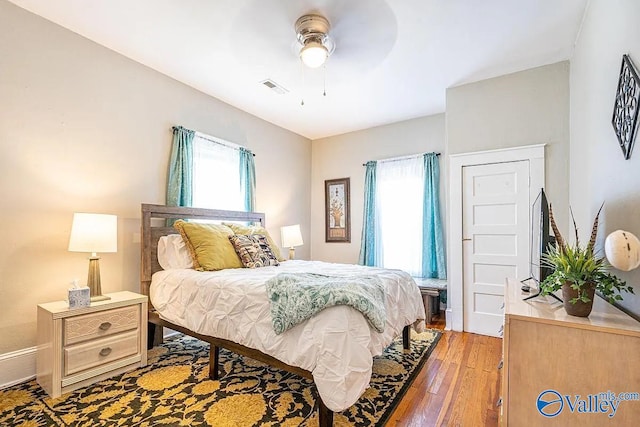 bedroom featuring light wood finished floors, visible vents, multiple windows, and a ceiling fan