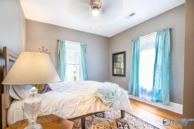 bedroom featuring a ceiling fan, wood finished floors, and visible vents