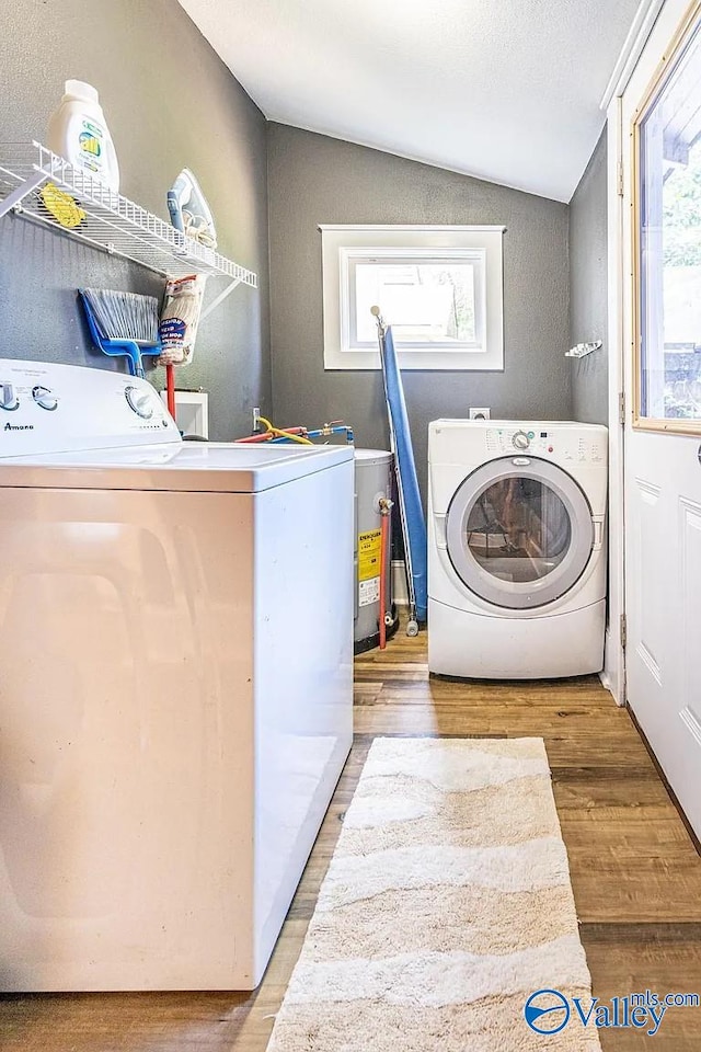 washroom with a wealth of natural light, laundry area, washer and dryer, and wood finished floors