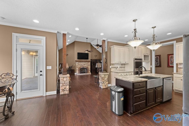 kitchen featuring sink, crown molding, an island with sink, stainless steel appliances, and light stone countertops