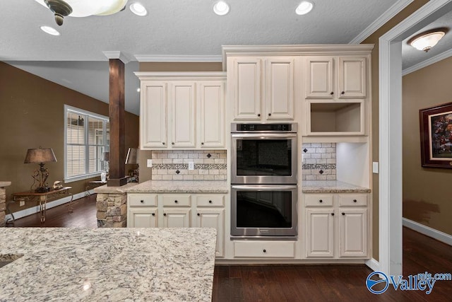 kitchen with light stone counters, stainless steel double oven, dark hardwood / wood-style floors, and crown molding