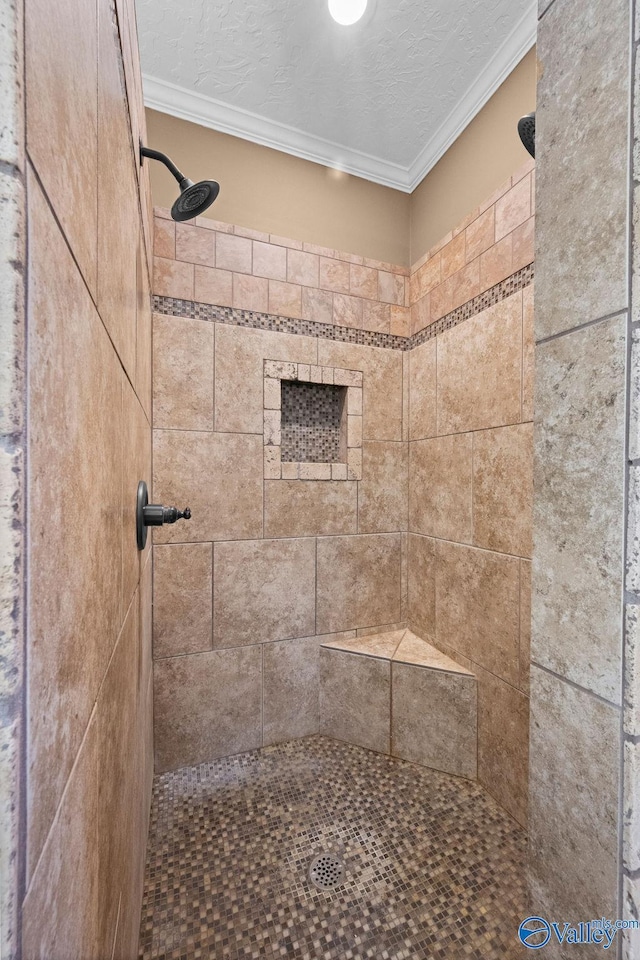 bathroom featuring a textured ceiling, ornamental molding, and tiled shower