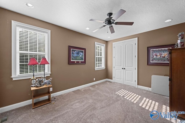 bedroom featuring light carpet, multiple windows, a closet, and a textured ceiling