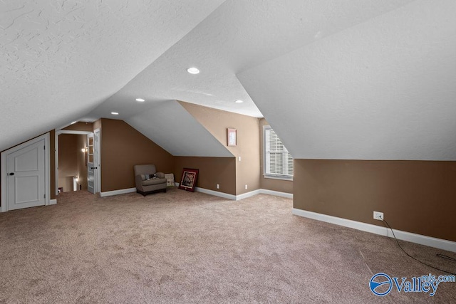 bonus room with vaulted ceiling, carpet flooring, and a textured ceiling