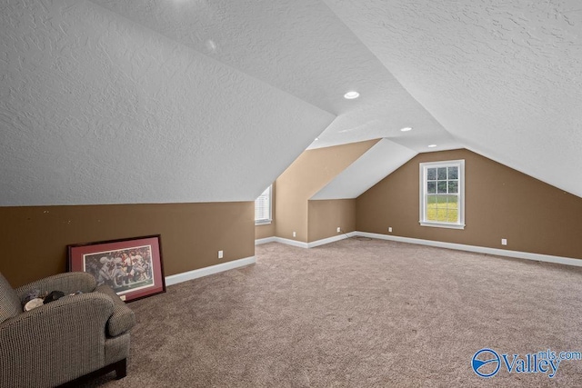 bonus room featuring lofted ceiling, a textured ceiling, and carpet flooring