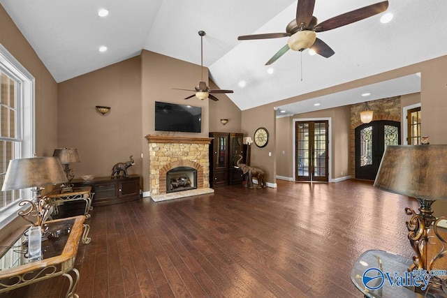 living room with a stone fireplace, dark wood-type flooring, high vaulted ceiling, and french doors