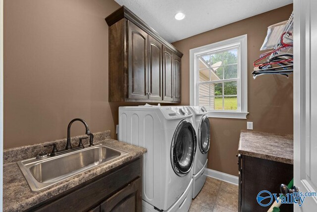 clothes washing area featuring sink, washing machine and dryer, cabinets, and light tile patterned flooring