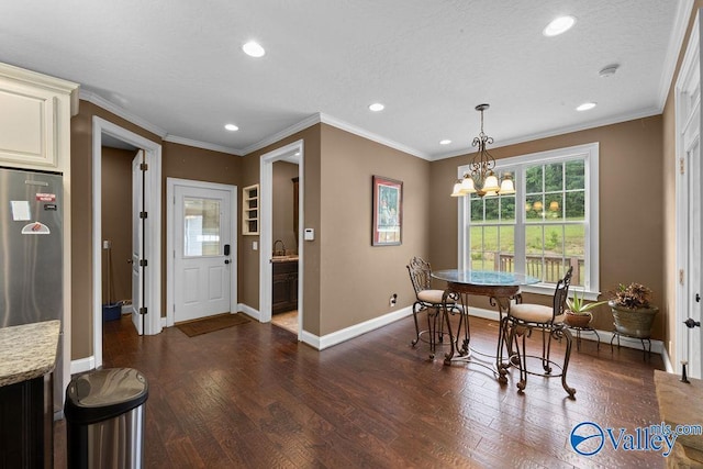 dining space with ornamental molding, dark wood-type flooring, sink, and a notable chandelier